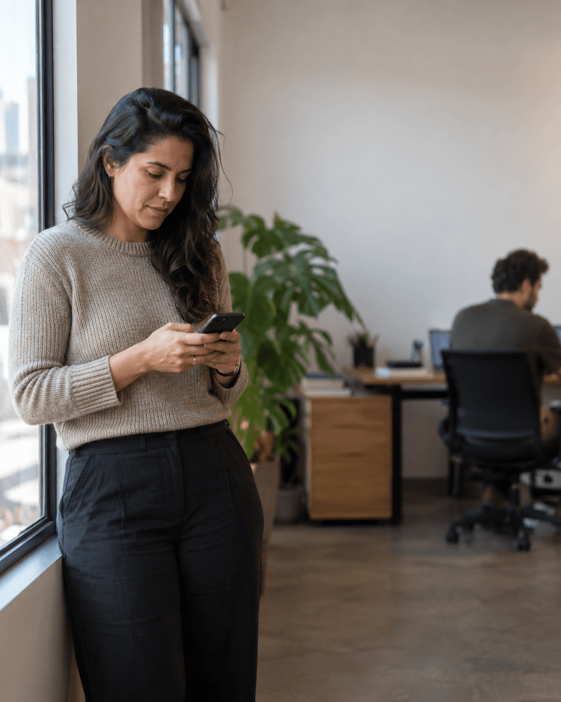 Colaboradora consultando o Portal do Colaborador no celular, no escritório